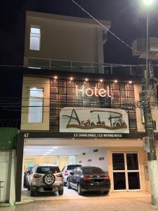 a hotel with two cars parked in front of it at Hotel e Pousada Areia da Praia in São Vicente