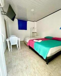 a bedroom with a bed and a table and a tv at Hotel Y Restaurante La Quinta in Cartagena de Indias