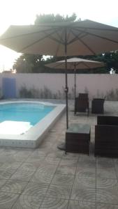 una sombrilla y sillas junto a la piscina en Gam Properties Guest House en Kololi