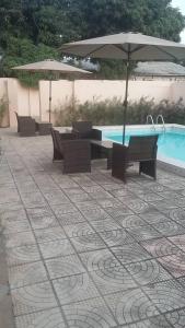 a patio with chairs and an umbrella and a pool at Gam Properties Guest House in Kololi