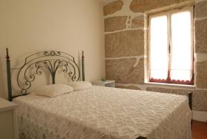a bedroom with a bed with a white comforter and a window at Casa do Tear in Macieira de Alcoba