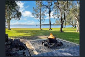 a fire pit in a park with a view of the water at Getaway Lakefront Environmental House on Lake Macquarie with Water View in Lake Munmorah