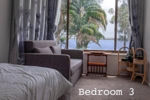 ein Schlafzimmer mit einem Sofa, einem Bett und einem Fenster in der Unterkunft Getaway Lakefront Environmental House on Lake Macquarie with Water View in Lake Munmorah