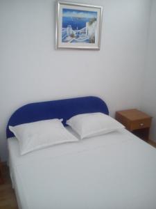 1 cama con cabecero azul y una foto en la pared en Apartments Filip, en Omiš