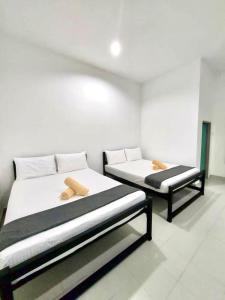 Belukar Lodges Private Homestay في بانتايْ سينانج: كان هناك سريرين يجلسون في غرفة مع سرير إضافي