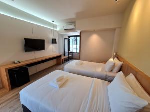 a hotel room with two beds and a flat screen tv at The Neuf@Ratchada in Bangkok