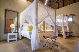 1 dormitorio con cama con dosel y silla en Kambaku Safari Lodge, en Reserva Timbavati