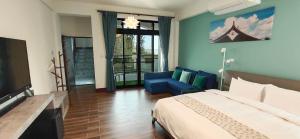 a bedroom with a bed and a couch and a tv at 嚨口十二之一民宿Longcall 12-1 in Jinning
