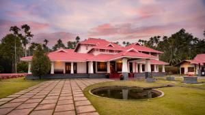 a house with a red roof and a pond at Wayanad Mace Mansion in Kenichira
