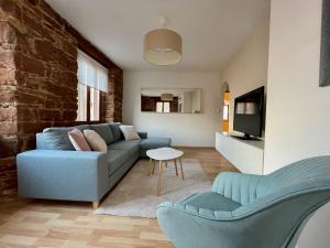 ein Wohnzimmer mit einem blauen Sofa und einem TV in der Unterkunft Appartement chaleureux et cocooning à Barr - Escapade chez Valentine in Barr