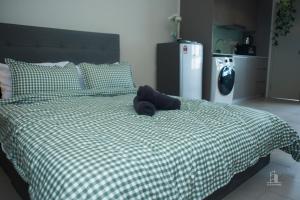 łóżko z zieloną i białą kołdrą z kapeluszem w obiekcie 9am-5pm, SAME DAY CHECK IN AND CHECK OUT, Work from Home, Comfy & Quiet Tamarind Suites-Cyberjaya by Flexihome-MY, w mieście Cyberjaya