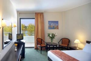 a hotel room with a bed and a desk and a window at Margarona Royal Hotel in Preveza