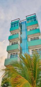 a tall building with a palm tree in front of it at Acacia Beach Hotel in Hulhumale