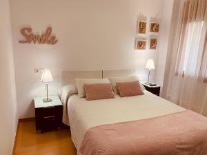 - une chambre dotée d'un lit avec deux lampes et un signe de sourire dans l'établissement Apartamentos Alcañiz, Gala, à Alcañiz