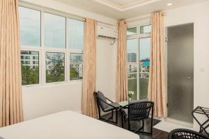 a room with windows and a table and chairs at Acacia Beach Hotel in Hulhumale