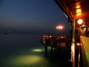 une jetée avec des personnes assises dans un restaurant la nuit dans l'établissement Langi Langi Beach Bungalows, à Nungwi