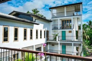 a white building with balconies and palm trees at Temptation in Hikkaduwa