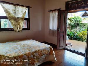 a bedroom with a bed and a large window at Pondok Kecil Bungalow in Ubud
