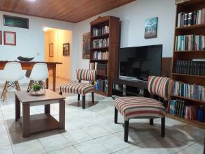 un soggiorno con TV, sedie e tavolo di Iguazu House a Puerto Iguazú