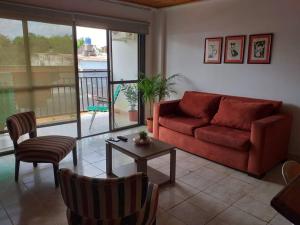 un soggiorno con divano rosso e tavolo di Iguazu House a Puerto Iguazú