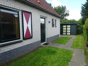 una casa con una cruz rosa a un lado. en Kustverhuur, Park Schoneveld, Zeemeeuw 164, en Breskens