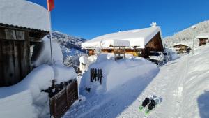 a house covered in snow with a snowboard in front of it at Ferienhaus & Ferienwohnung Wiñay Wayna Gotschna Blick Klosters in Klosters Serneus