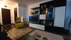 a living room with a tv and a yellow chair at Apartament Coșbuc in Baia Mare