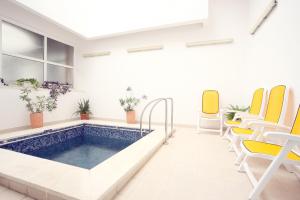 a swimming pool in a waiting room with yellow chairs at Hotel International in Baile Felix