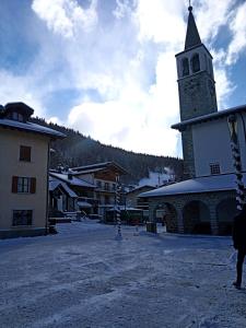 a church with a clock tower in a snow covered village at MadeBoutique Rooms in Madesimo