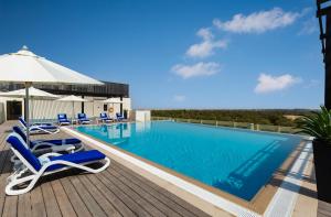 - une piscine avec des chaises et un parasol sur la terrasse dans l'établissement Millennium Place Mirdif Apartments, à Dubaï