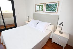 a white bedroom with a white bed and a window at Alojamientos Libertad in Yecla