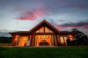 a house with a large window on a field at Cuddfan Lodge on a Gorgeous Private Lake in Newport