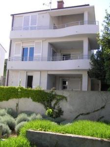 Cette maison blanche dispose d'un balcon. dans l'établissement Apartments Paska Preko, à Preko