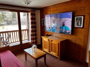 - un salon avec une télévision à écran plat sur un mur en bois dans l'établissement Les Alpages location appartement 202, à Lanslebourg-Mont-Cenis