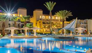 una piscina por la noche con palmeras y edificios en Amarina Abu Soma Resort & Aquapark, en Hurghada