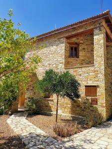 un edificio de piedra con un árbol delante de él en Unique Stonehouse Traditional Villa in Ayia Anna, en Ayia Anna