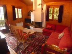 a living room with a red couch and a chair at Charming chalet with panoramic view and private garage in Gruyère in Gruyères