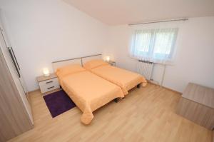 sypialnia z łóżkiem z pomarańczową pościelą i oknem w obiekcie Apartament VV w Puli