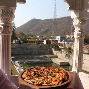 
a pizza sitting on top of a table next to a river at Hotel Bundi House in Būndi
