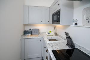 a white kitchen with white cabinets and a sink at Lavender Lodge in Arundel