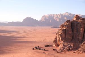 a group of people standing near a large rock in the desert at Desert Bird Camp in Wadi Rum