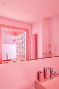 ein rosafarbenes Bad mit einem Waschbecken und einem Spiegel in der Unterkunft THULITE casa vacanze in Gaeta