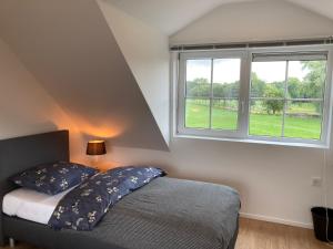 1 dormitorio con cama y ventana en Vakantiehuis Ervedriestreek, en Den Ham