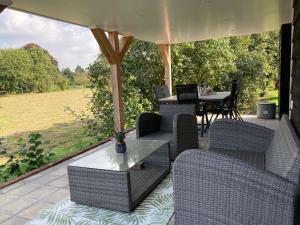 een patio met stoelen en een tafel met uitzicht op een veld bij Vakantiehuis Ervedriestreek in Den Ham
