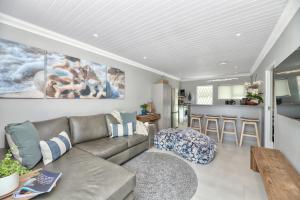 Una sala de estar con un sofá y una cocina. en Spring Tide on 28 Main Struisbaai, en Struisbaai