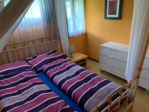1 dormitorio con cama con sábanas a rayas y ventana en Naturnahe Wohnung für 1 - 4 Personen, en Brienz