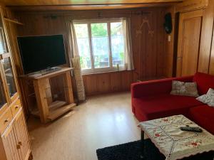 un soggiorno con divano rosso e TV a schermo piatto di Naturnahe Wohnung für 1 - 4 Personen a Brienz