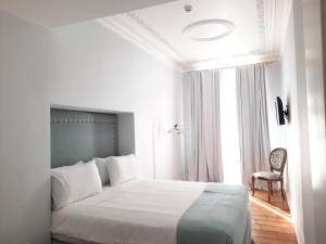 a white bedroom with a large bed and a chair at Palácio do Visconde - The Coffee Experience in Lisbon