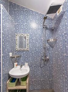 a blue tiled bathroom with a sink and a shower at Pequena Casa rústica com piscina in Penafiel
