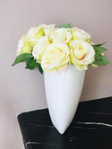 a white vase with yellow roses in it at Bienvenue chez l'habitant in Provins